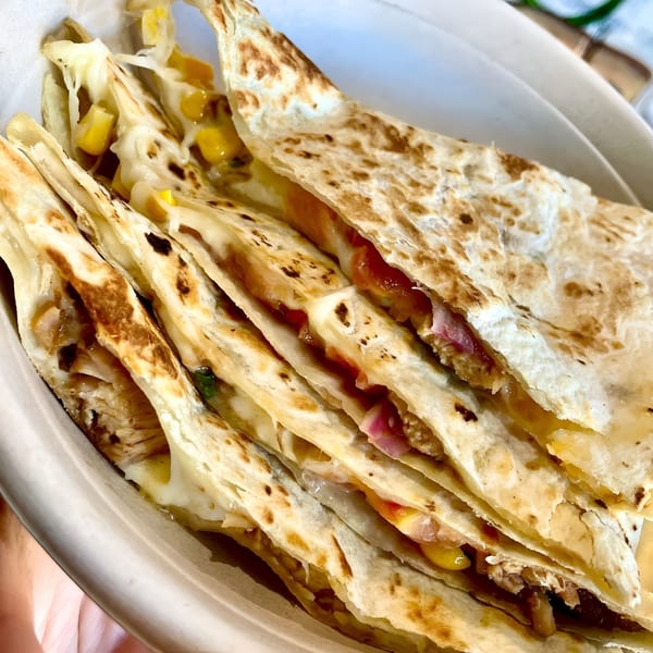Stacked quesadilla wedges revealing melted cheese, corn, red onion, and chicken filling.